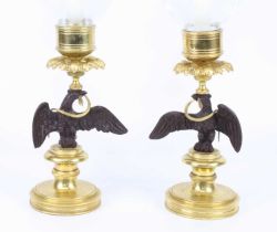 A pair of bronze and gilt brass pedestal candlesticks, each with clear glass storm lantern shades,