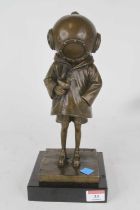 A bronzed metal figure of a young girl wearing a vintage style diver's helmet, shown standing,