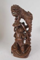 A 20th century Chinese carved hardwood figure group of a warrior fighting a shi shi, h.30cm