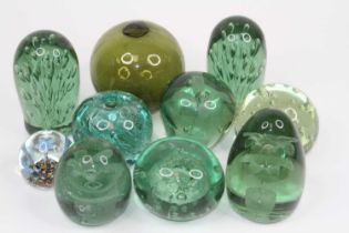A collection of Victorian green glass dumps, each with internal decoration; together with a green