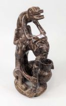 An African carved hardstone figure group of an elderly man surmounted by a lizard, h.40cm