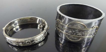 A silver and engraved hinged bangle; together with a silver hinged cuff bangle (2) Both heavily