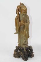 A Chinese hardstone carving of a scholar, modelled standing holding a staff and peach, on