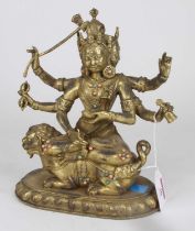 A gilt metal figure of a Tibetan deity modelled seated on shi shi, height 23cm