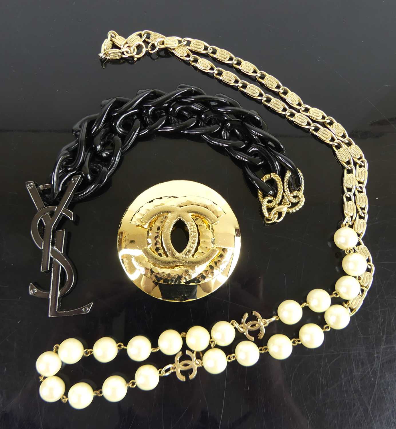After Coco Chanel - a gilt metal brooch; together with an Yves Saint Laurent style necklace and
