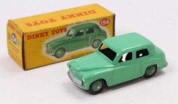 A Dinky Toys No. 154 Hillman Minx saloon, comprising green body and green ridged hubs, housed in the