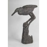 A bronzed model of a bird, shown perched upon a stump, h.50cm