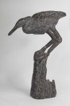 A bronzed model of a bird, shown perched upon a stump, h.50cm