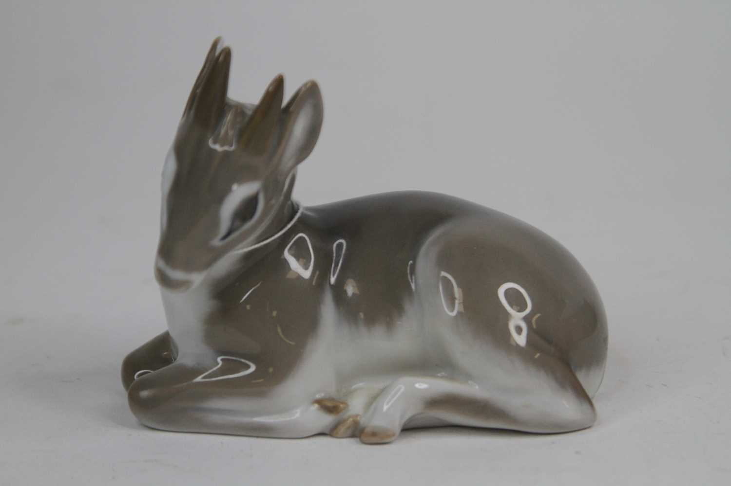 A Royal Copenhagen porcelain model of a fawn, shown recumbent, length 11cm Appears in good