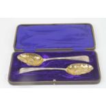 A pair of George III silver berry spoons, each having a repousse decorated shaped bowl and