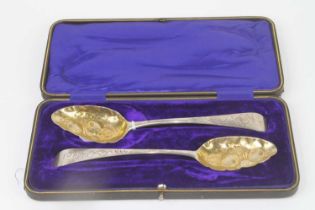 A pair of George III silver berry spoons, each having a repousse decorated shaped bowl and