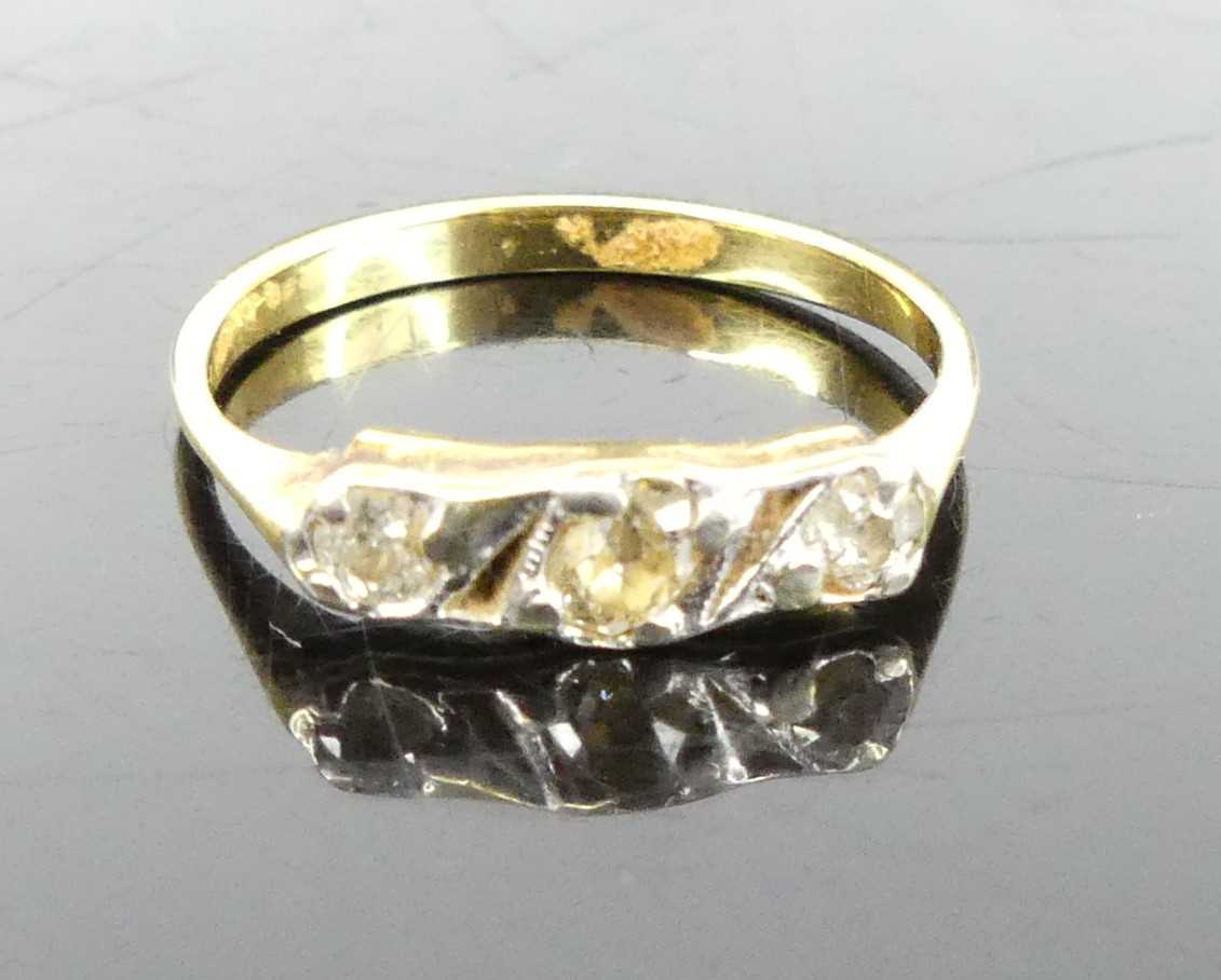 A yellow metal diamond set ring, arranged as three graduated round cuts in a line setting,