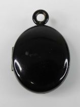 A Victorian jet oval mourning locket, h.34mm (excluding pendant bale), in associated brown leather