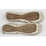 A pair of vintage silk children's ballet pump shoes, each bearing signatures to the sole