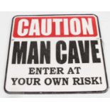 A painted cast iron sign inscribed Caution Man Cave, 25x25cm