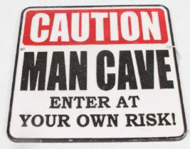 A painted cast iron sign inscribed Caution Man Cave, 25x25cm
