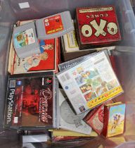 A box containing various consoles, video games, and various board games to include Micro Machines