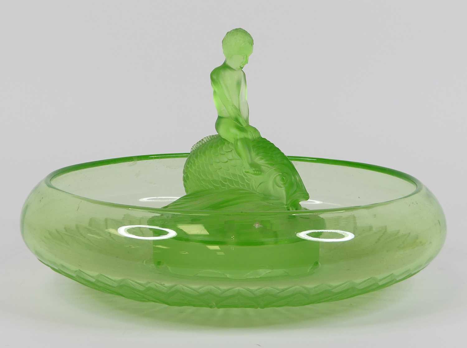 An Art Deco green glass centrepiece, in the form of a boy riding a fish, dia. 35cm Chips to the base