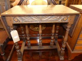 A joined oak dropflap low occasional table, having a carved frieze, raised on turned and square
