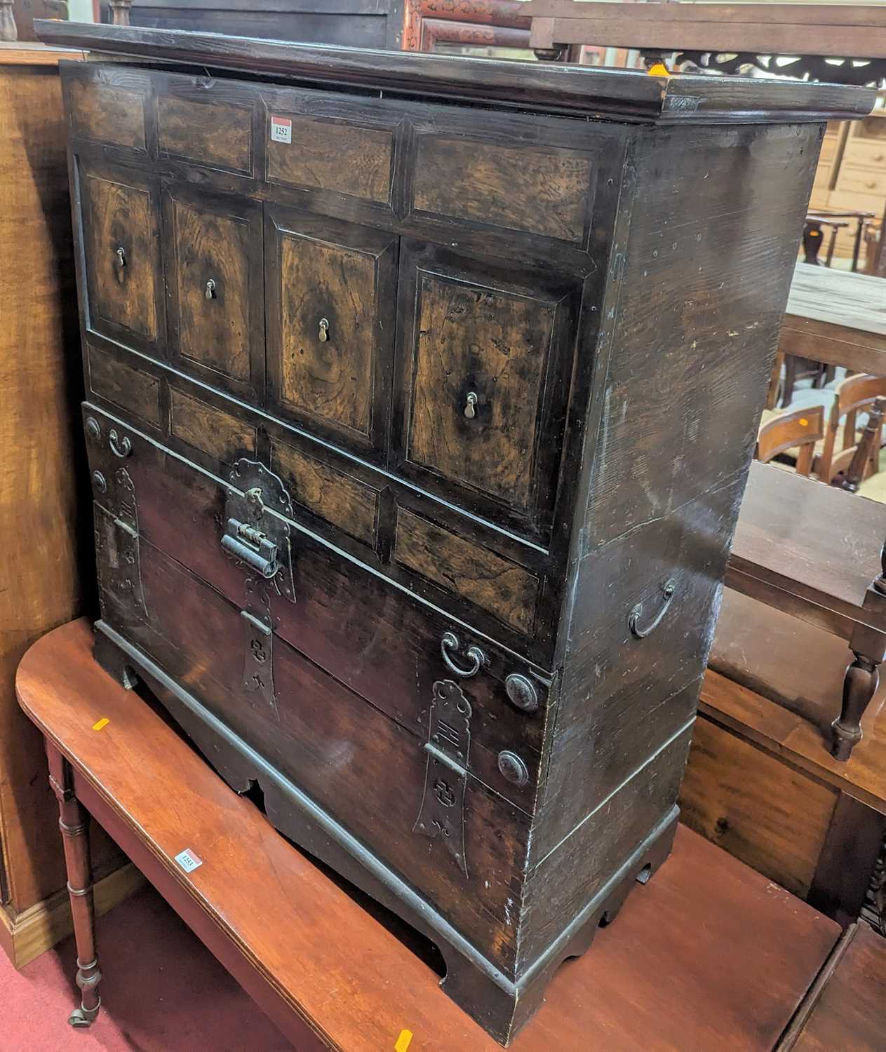 An Eastern elm and iron mounted side cupboard, having four removable upper panels over lower fall