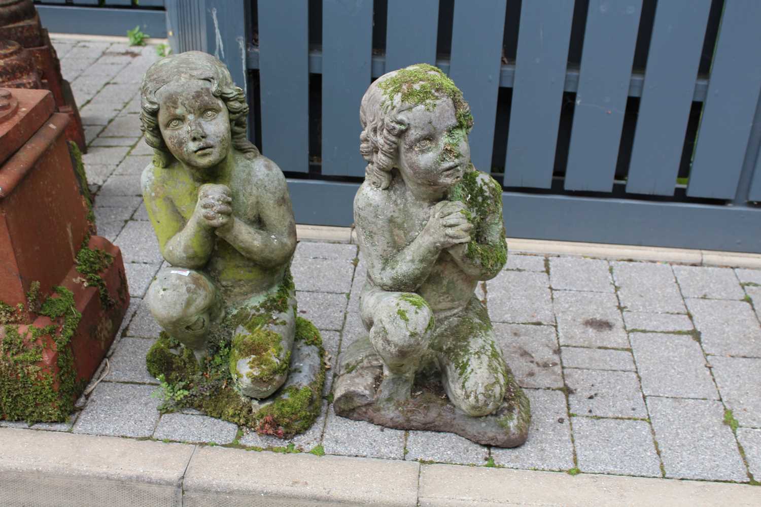 A pair of reconstituted stone garden figures, each modelled as a kneeling young girl, to