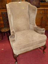 An early 20th century walnut framed and hide upholstered wingback armchair, having a squab cushion