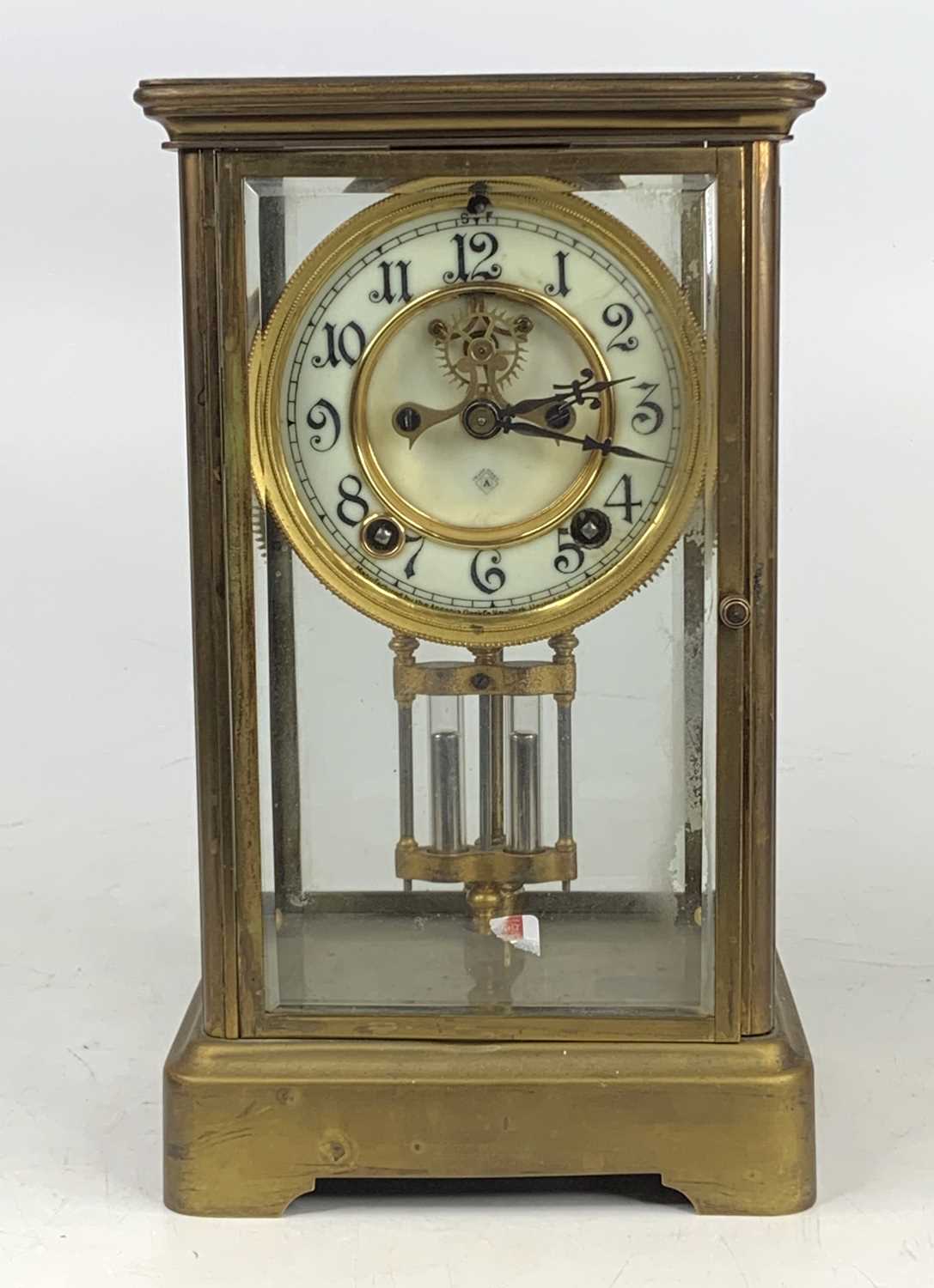 A circa 1900 lacquer brass four glass mantel clock, the dial with visible escapement and having faux