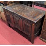 An 18th century provincial oak three panelled hinge top coffer, later relief carved to front,