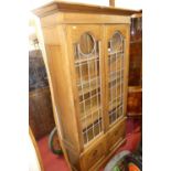 An Arts & Crafts oak double door lead glazed bookcase, with interior shelves over floral stylised