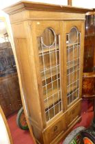 An Arts & Crafts oak double door lead glazed bookcase, with interior shelves over floral stylised