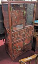 A 20th century Chinese red lacquered side cabinet, having twin glazed upper doors, and interior