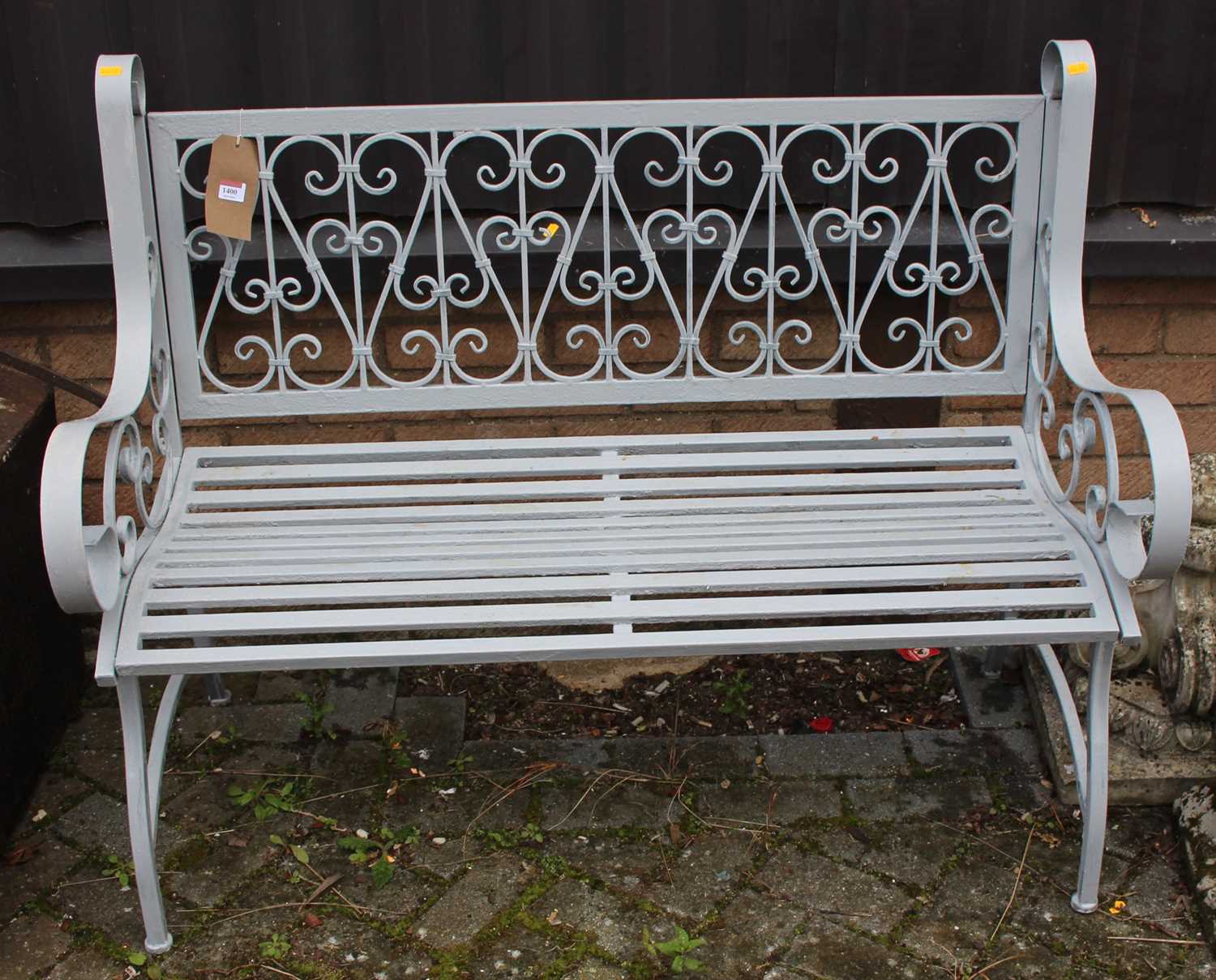 A grey painted metal two-seater garden bench, having floral scroll and strapwork design, width