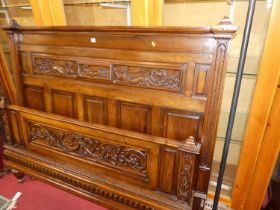 An early 20th century French relief carved walnut king size bedstead, the headboard with