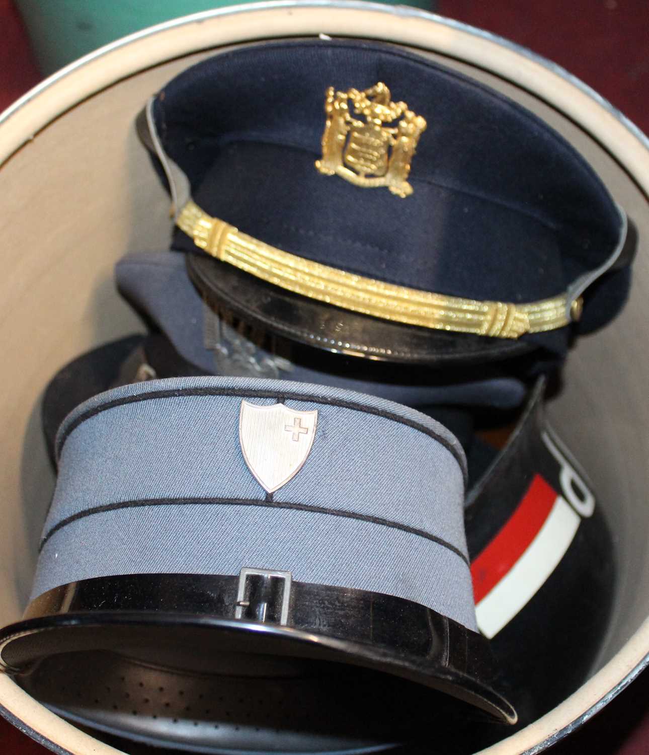 Two boxes of assorted headwear, to include German Military Police visor caps etc