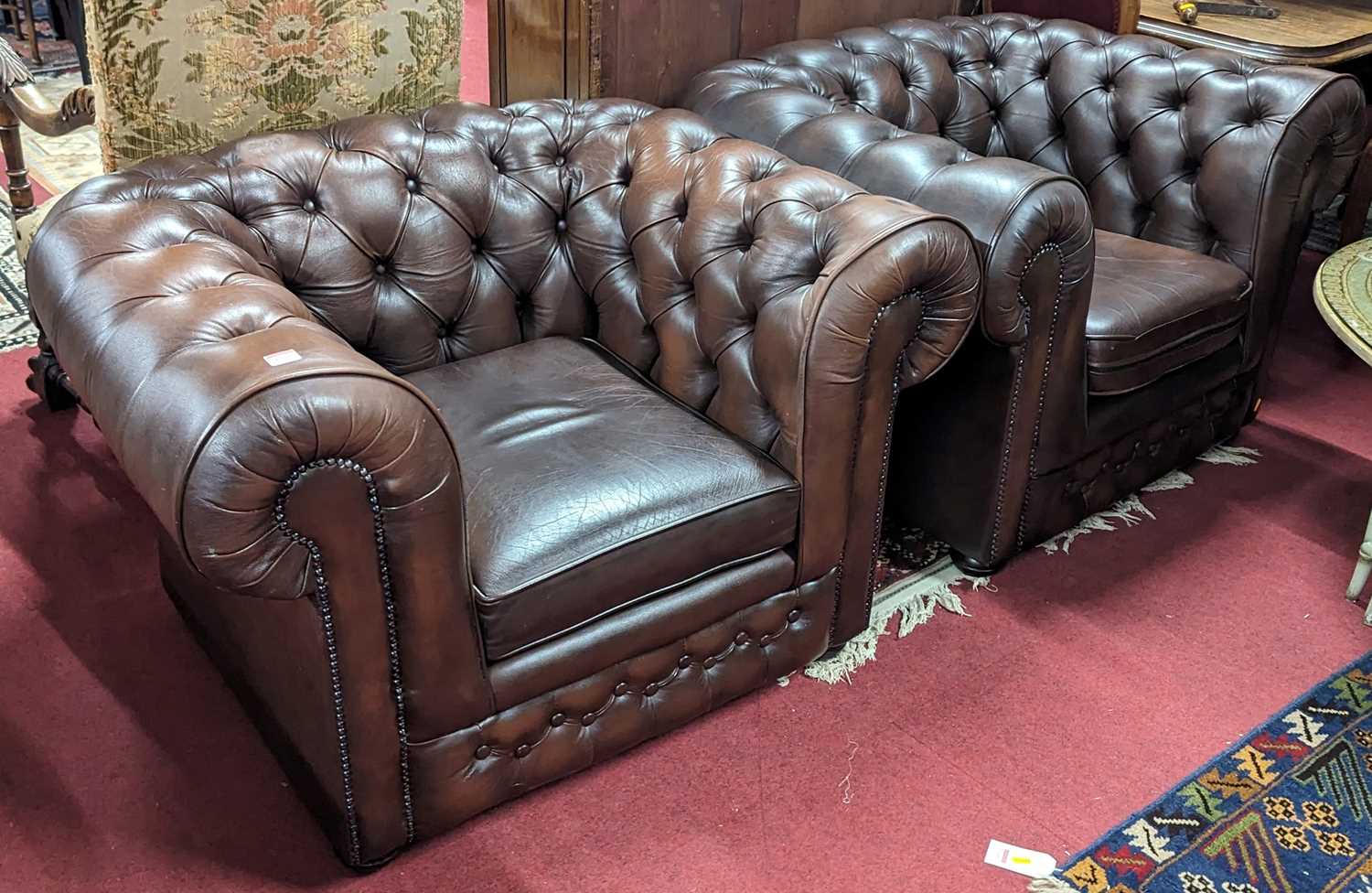 A pair of contemporary tan leather buttoned and further brass studded Chesterfield armchairs by