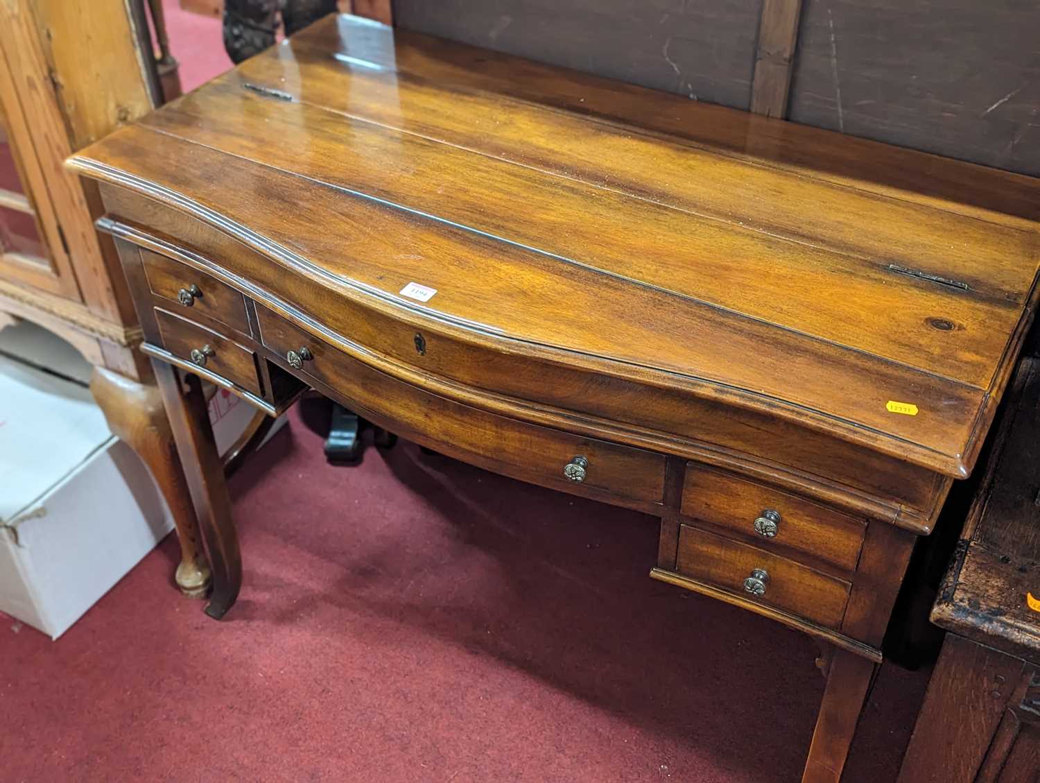 A contemporary cherry wood kneehole serpentine front writing desk, having a hinged pull-out