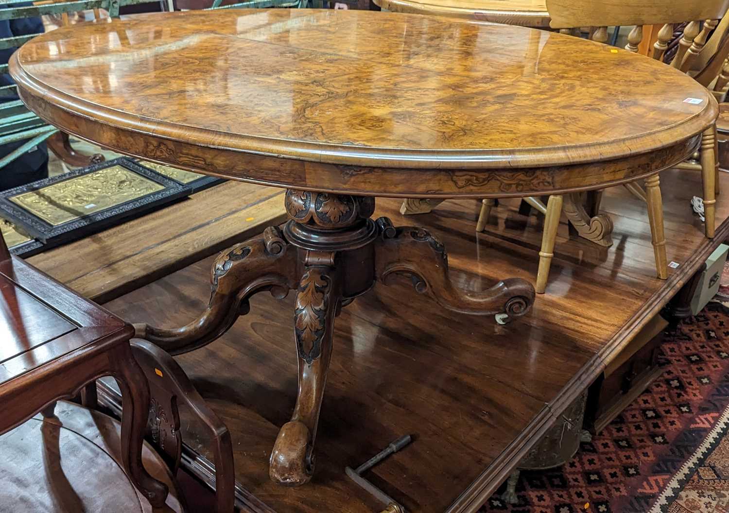 A mid-Victorian figured walnut oval tilt-top pedestal breakfast table, raised on acanthus carved and