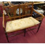 An Edwardian beech two-seater salon settee, having a mustard floral damask fixed pad seat, w.108cm