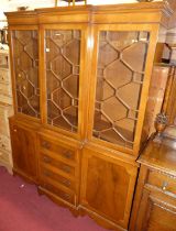 A reproduction yew wood breakfront bookcase, having three astragal glazed upper doors over four