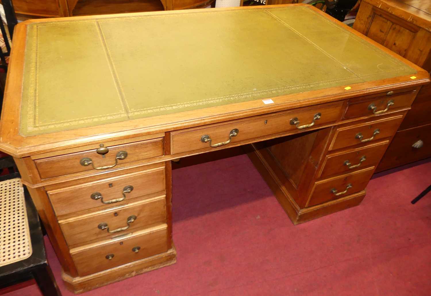 An early 20th century walnut and gilt-tooled green leather inset twin pedestal writing desk,