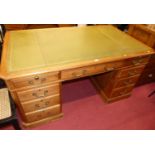 An early 20th century walnut and gilt-tooled green leather inset twin pedestal writing desk,