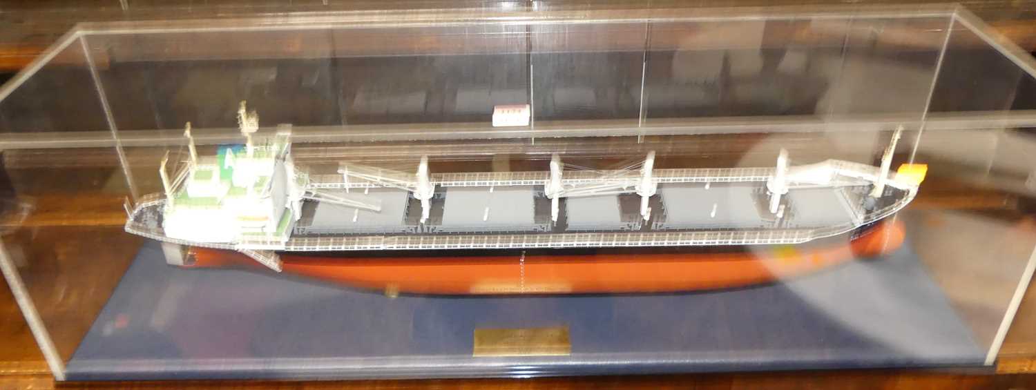 A scale model of the "MV Doma Hortencia II" housed in a perspex display case, with engraved brass