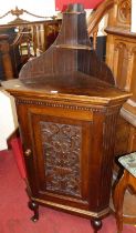 An early 20th century floral relief carved oak single door freestanding corner cupboard, on squat