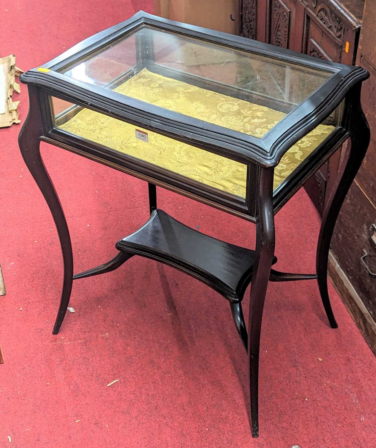 An Edwardian stained walnut hinged top bijouterie table, raised on slender cabriole supports, united