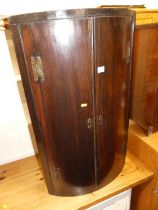 A George III mahogany bowfront double door hanging corner cupboard; together with a walnut single