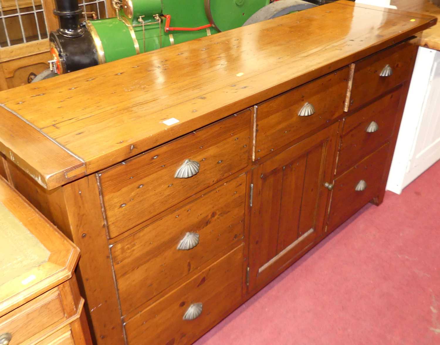 A contemporary stained pine sideboard, fitted with seven drawers and central cupboard door, w.172cm