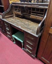 A 1930s oak kneehole roll-top desk, having a divisional interior over a central frieze drawer,