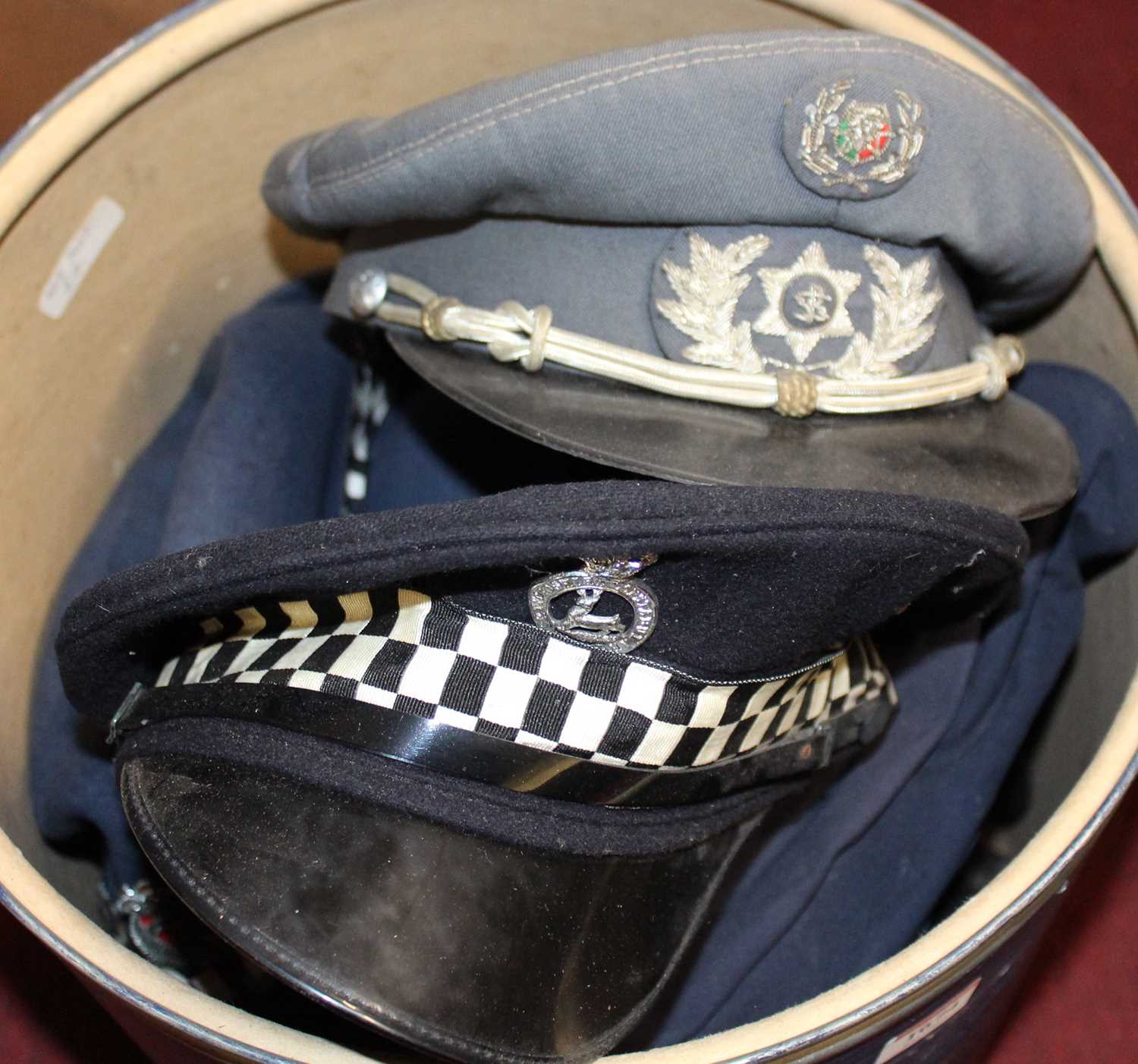 Two hat boxes of various military headwear, to include visor caps, female officers police examples