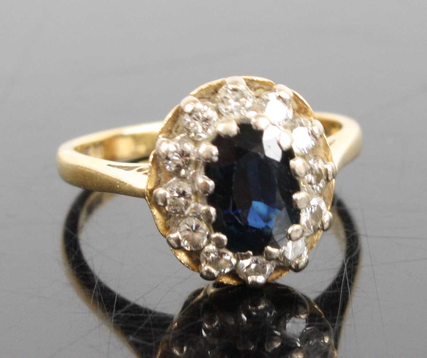 An 18ct yellow and white gold, sapphire and diamond oval cluster ring, featuring a centre oval