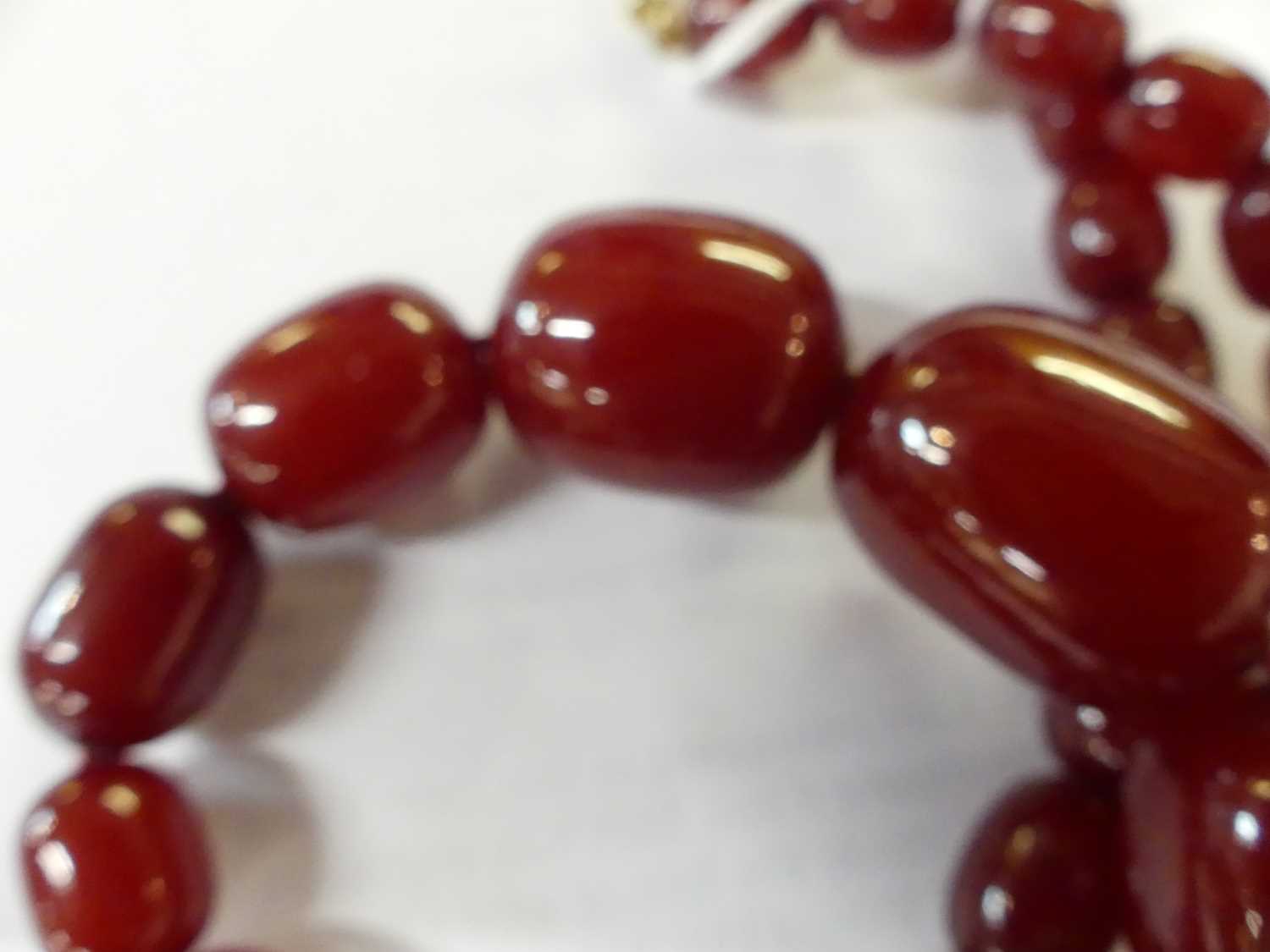 A cherry amber single string necklace, arranged as 40 graduated barrel beads, the largest w.25mm, - Image 8 of 14